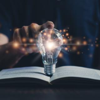 Illuminated lightbulb on book Illuminated lightbulb on book
