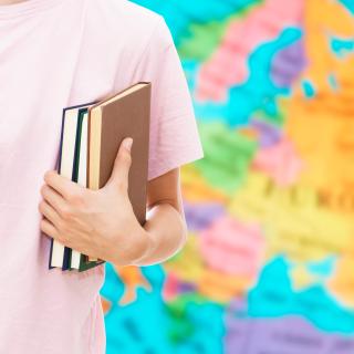 Student holding a book and backpack