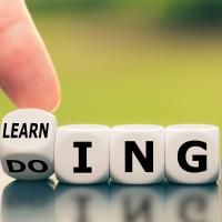 Dices showing the words ‘learning’ and ‘doing’